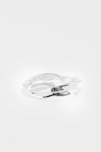 A polished silver ring with a sculptural, twisted ribbon-like form, photographed on a seamless light gray background.