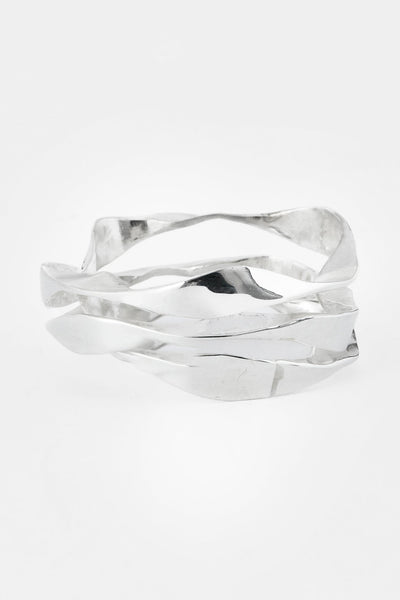 A silver ring with a modern, organic wavy design and a textured, hammered finish, photographed on a seamless light gray background.